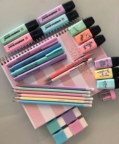 several pens and pencils sitting on top of a pink notepad with different designs