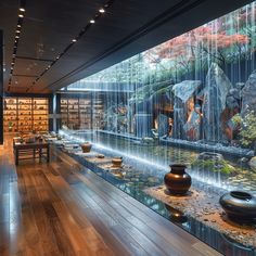 a room filled with lots of different types of vases and bowls on display in front of a waterfall