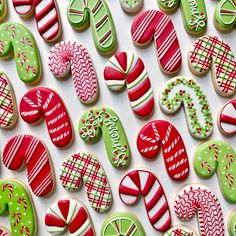 many decorated cookies are displayed on a white surface with candy canes and candies