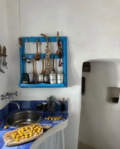 a kitchen with blue counter tops and wooden utensils hanging on the wall above it