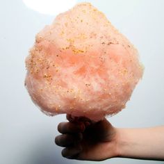 a person holding up a pink doughnut with sprinkles on it