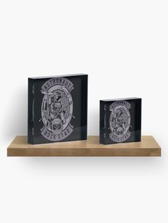 two black glass plaques on a wooden shelf