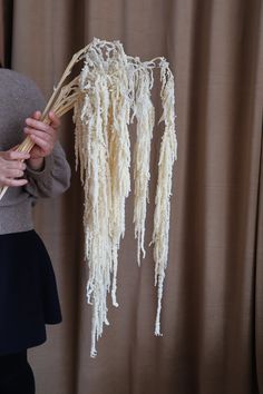 a woman holding up some kind of plant with long stalks attached to it's stems