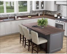 a kitchen with white cabinets and an island in the middle, surrounded by stools