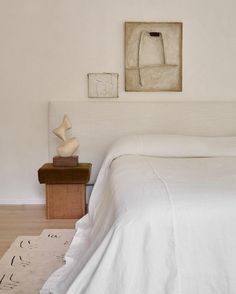 a white bed sitting in a bedroom next to a painting