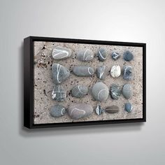 a group of rocks sitting on top of a sandy beach under a black framed canvas