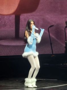 a woman in a blue and white outfit singing on stage