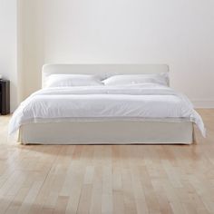 a white bed sitting on top of a hard wood floor