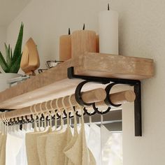 a wooden shelf with some curtains hanging from it's sides and candles on the other side