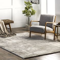 a living room with a chair, table and rug on the floor in front of it