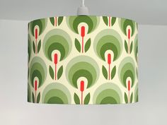 a green and red lampshade hanging from a ceiling light fixture with an art deco design