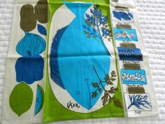 two pieces of cloth with blue and green designs on them sitting on a white surface