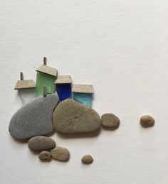 some rocks and small houses sitting on top of a white surface with one house in the middle