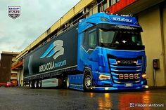 a blue semi truck parked in front of a building