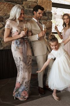 a group of people standing next to each other holding wine glasses in their hands and posing for the camera