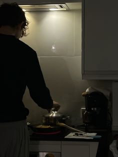 a woman is cooking in the kitchen with her hand on the stove and she is looking at the light