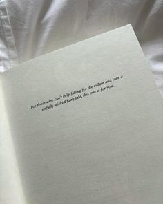 an open book sitting on top of a bed next to a white sheet and pillow