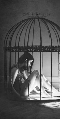 a woman sitting on the floor in front of a cage