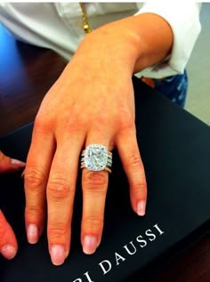 a woman's hand on top of a book with a diamond ring in it