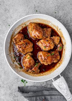 a white bowl filled with meat covered in sauce