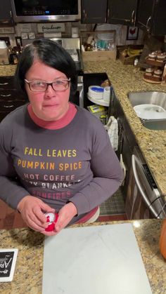 a woman sitting at a kitchen counter with a knife in her hand and a pumpkin on the counter