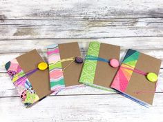 three small notebooks are lined up on top of each other, with buttons and string