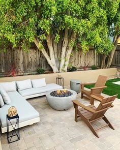 an outdoor living area with couches, chairs and a fire pit in the middle