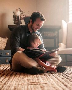 a man sitting on the floor reading a book to a child