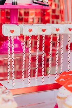 there are many cupcakes on sticks in the shape of hearts and arrows with red polka dots