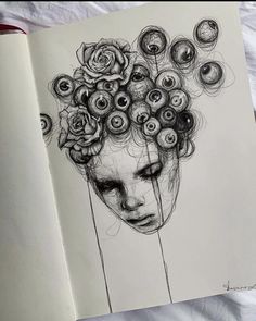 a drawing of a woman's face with flowers in her hair on top of an open book