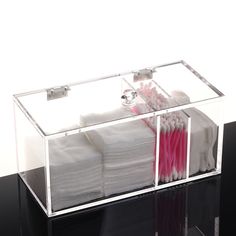 a clear acrylic box filled with lots of white towels and pink toothbrushes