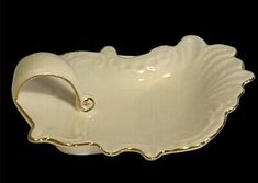 a white porcelain dish with gold trimmings on the edge and an oval handle