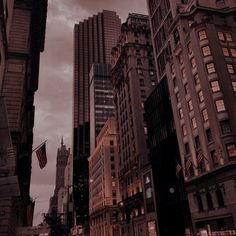 a city street filled with lots of tall buildings under a cloudy sky in the evening