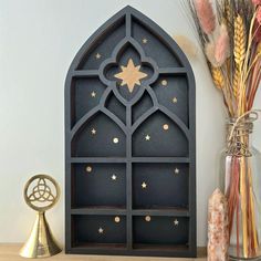 a decorative shelf with a star on it next to a vase and some dried flowers