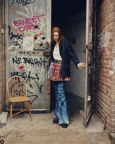 a woman standing in an open doorway with graffiti on the walls