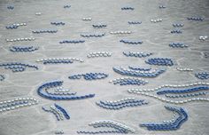 many blue and white beads are arranged in the shape of an octopus on cement ground