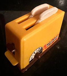 a yellow toaster sitting on top of a black counter next to a white object