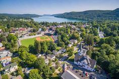 an aerial view of a baseball field in the middle of a town surrounded by trees