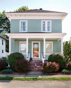 a green house with white trim and two story