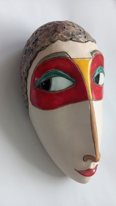 a white mask with red, yellow and blue painted on it