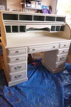 a white desk with lots of drawers sitting on top of a blue tarp covered floor