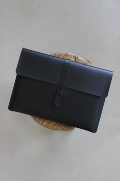 a black leather clutch bag sitting on top of a wooden table next to a wicker basket