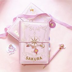 a pink book with charms and stickers on it sitting next to some other items