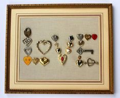 there are many different types of heart shaped pins in this shadow box with gold trim