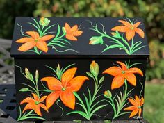 a painted box sitting on top of a metal table next to a black chair and trees