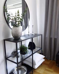 a black and white room with a mirror on the wall next to a shelf filled with plants