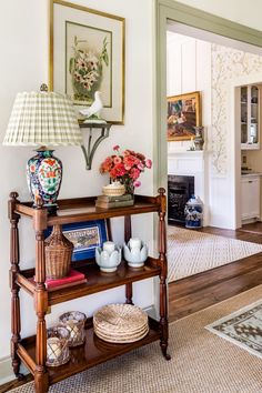 a shelf with vases and flowers on it in a living room next to a doorway