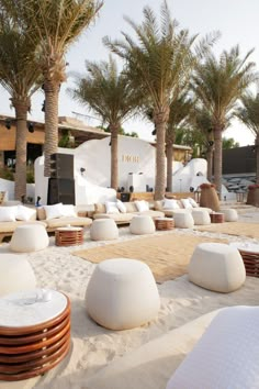 an outdoor seating area with white cushions and palm trees in the backgrouds