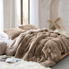 an unmade bed with fluffy blankets and pillows