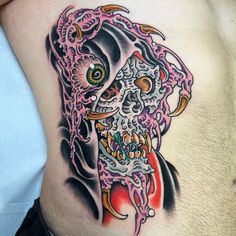 a man's stomach with a colorful skull tattoo on his side and an octopus in the middle